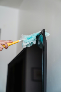 A person dusting a TV screen