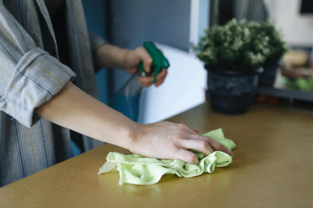 A person cleaning a table with a cleaning cloth